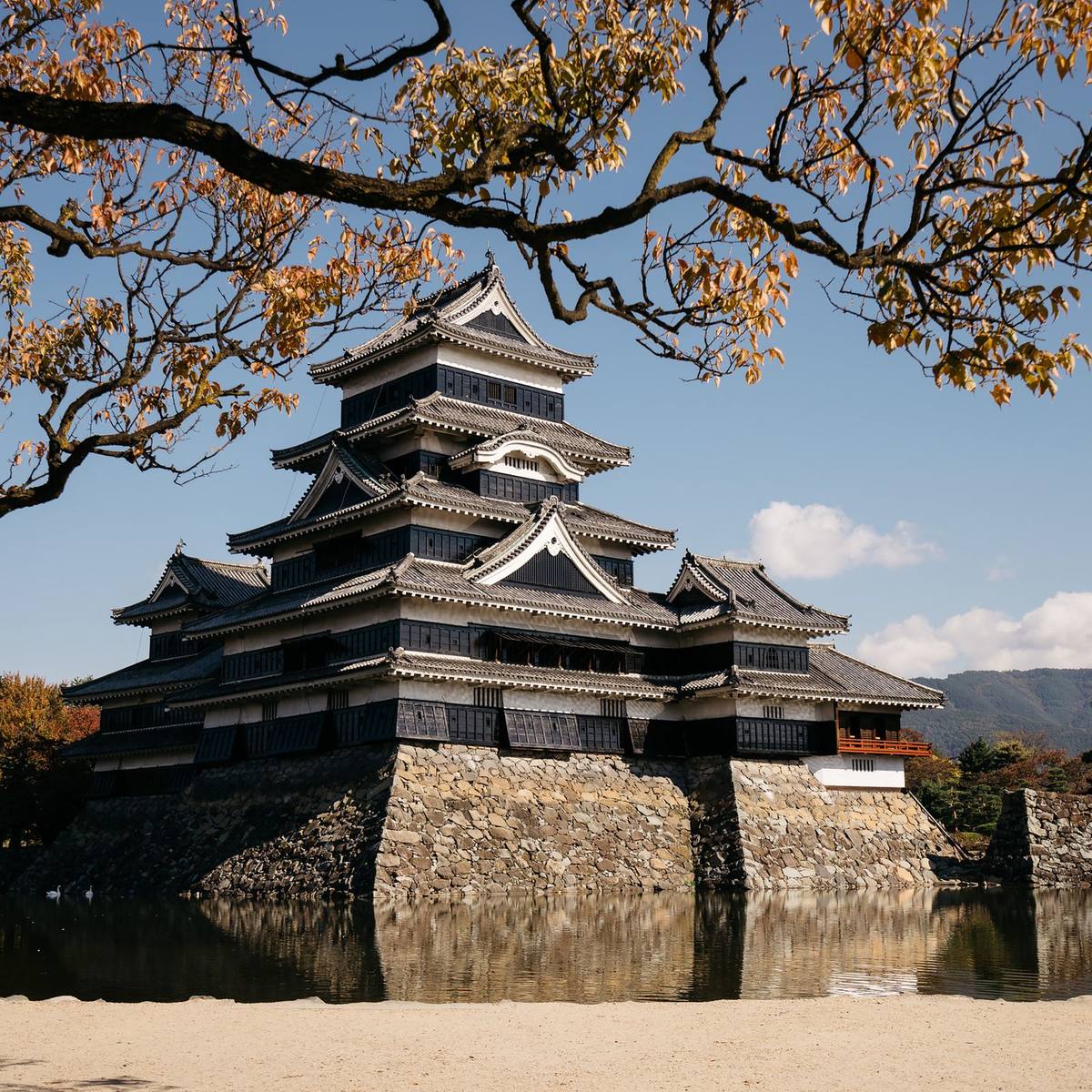 Matsumoto Castle's black keep reflected in the surrounding moat in autumn